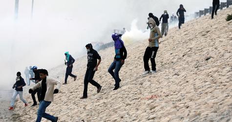 Anti-government protesters run down from the fly-over of the main highway as riot police fires teargas to disperse them during clashes after the funeral procession of Jafar Jassim Razi in&nbsp;Budaiya