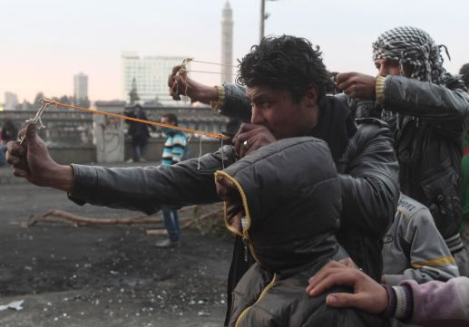 Protesters use slingshots to launch stones at riot police during clashes near Qasr el-Nil bridge, in&nbsp;Cairo