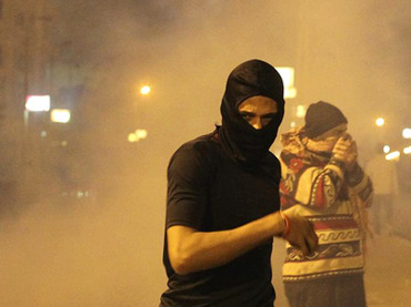 Protesters opposing Egyptian President Mohamed Mursi and the Muslim Brotherhood run from tear gas during clashes with police in front of the Presidential Palace in&nbsp;Cairo
