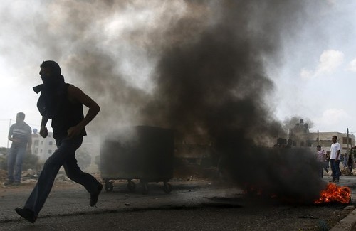 Palestinian protester runs during clashes with Israeli troops near the West Bank village of Silwad near&nbsp;Ramallah