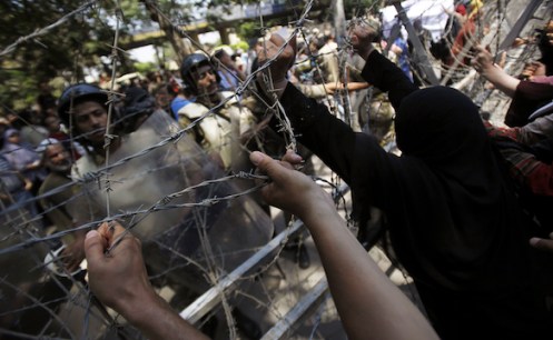 Female members of the Muslim Brotherhood and supporters of ousted Egyptian President Mursi try to remove a barbed wire fence in Cairo