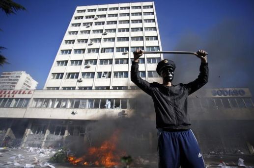 618104-a-protester-stands-near-a-fire-set-in-front-of-a-government-building-in-tuzla