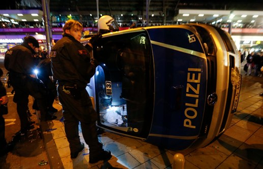 German riot police officers use torches to look for their personal belongings in an overturned police van following a demonstration by German far-right groups in&nbsp;Cologne