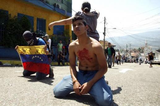 Boy with blood on his chest kneels in front of police after student Kluiver Roa died during a protest in San&nbsp;Cristobal