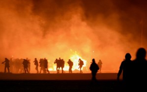 Smoke billows as migrants start a fire during clashes with police at the "Jungle" migrant camp in Calais, northern France, on October 23, 2016 on the eve of the camp's planned evacuation. On the eve of the demolition of the Calais "Jungle" camp, French officials handed out flyers in several languages notifying migrants of the camp's imminent closure and urging them to abandon their dreams of reaching Britain. / AFP PHOTO / DENIS CHARLET