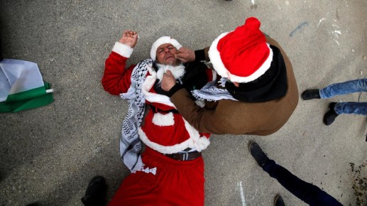 Man tends to a Palestinian protester, dressed as Santa Claus, after inhaling tear gas fired by Israeli troops during clashes in the West Bank city of&nbsp;Bethlehem