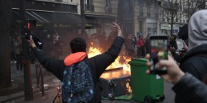 A young man gestures in front of burning dustbins which obstruct the street, during a protest of students against police brutality, following the alleged rape of Theo, next to the "Lycee Voltaire" secondary school in Paris, on February 23, 2017. / AFP PHOTO / GEOFFROY VAN DER HASSELT
